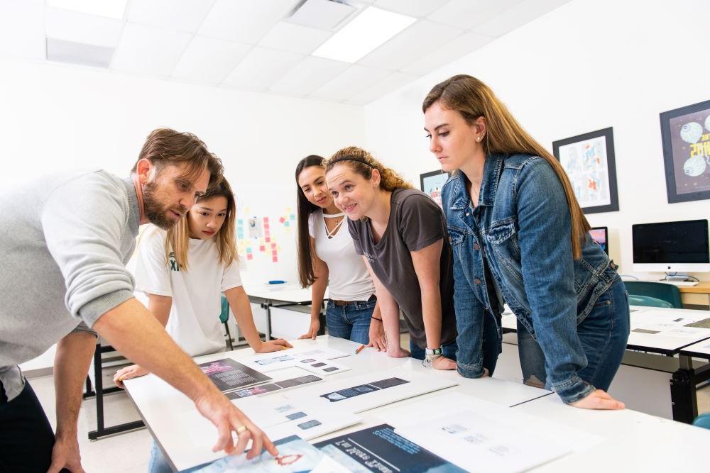 male teacher with female students in a design lab